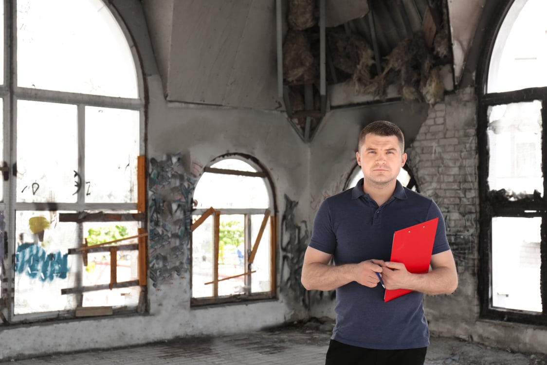 Male Insurance Adjuster Inspecting Abandoned Building, Outdoors